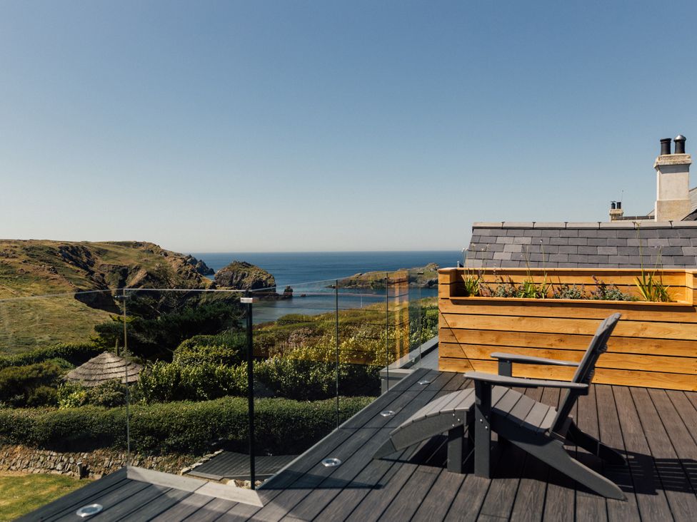 An outdoor space with a chair and planter overlooking the sea at Trevean in Mullion