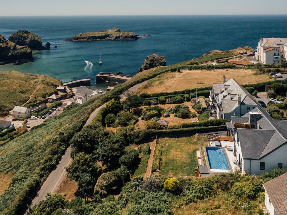 An aerial view of the coastline with a harbor and houses at Trevean in Mullion