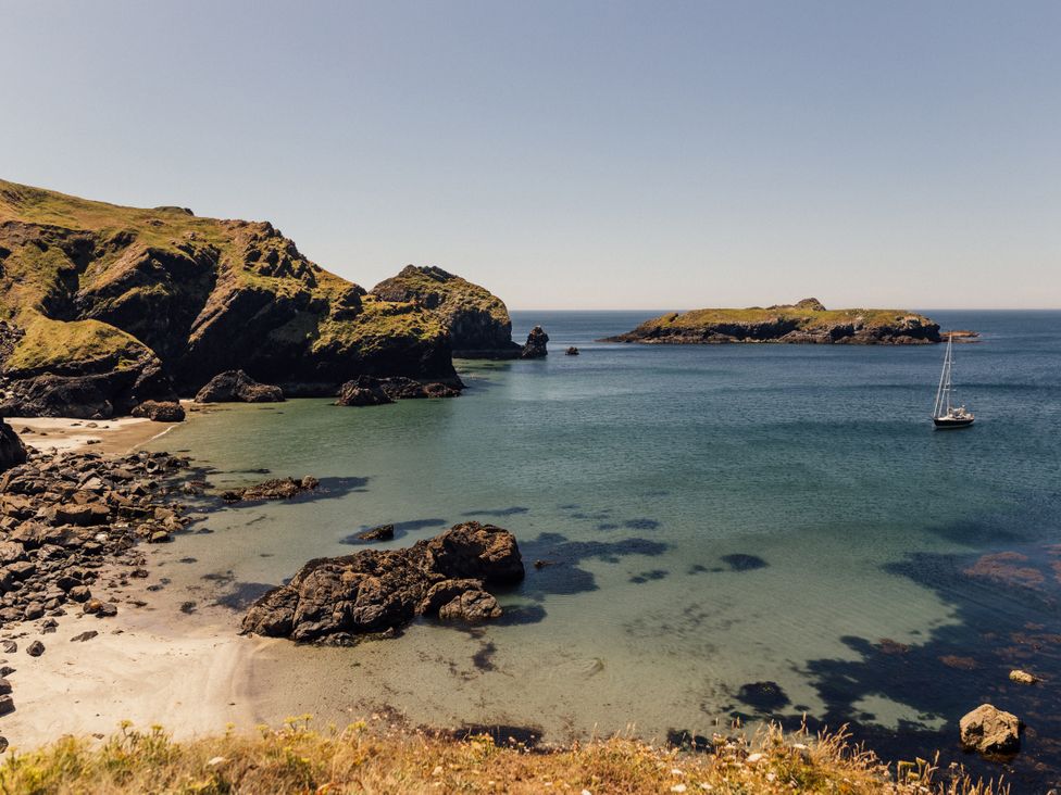 A coastal scene with a boat in the water and rocky shore at Trevean in Mullion