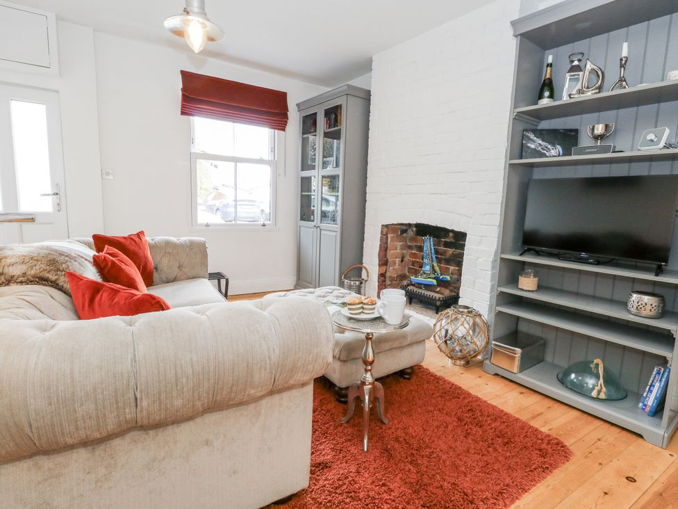 A living room with a sofa and television at Fisherman’s Cottage