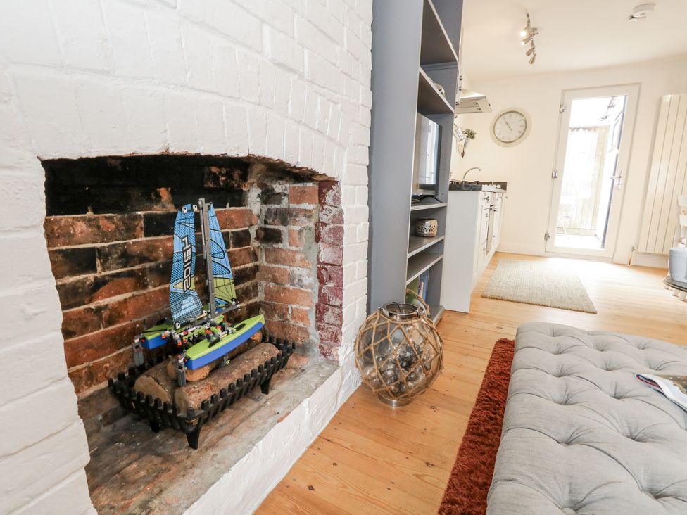 A living room with a model sailboat in the fireplace at Fisherman’s Cottage
