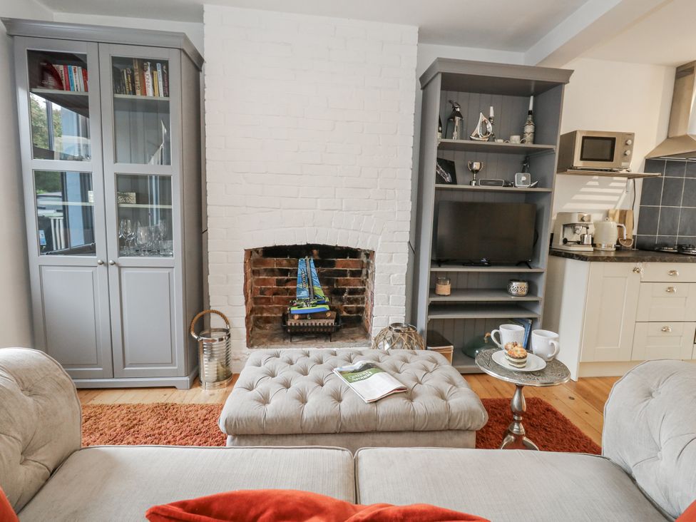 A living room with a fireplace and bookcase at Fisherman’s Cottage