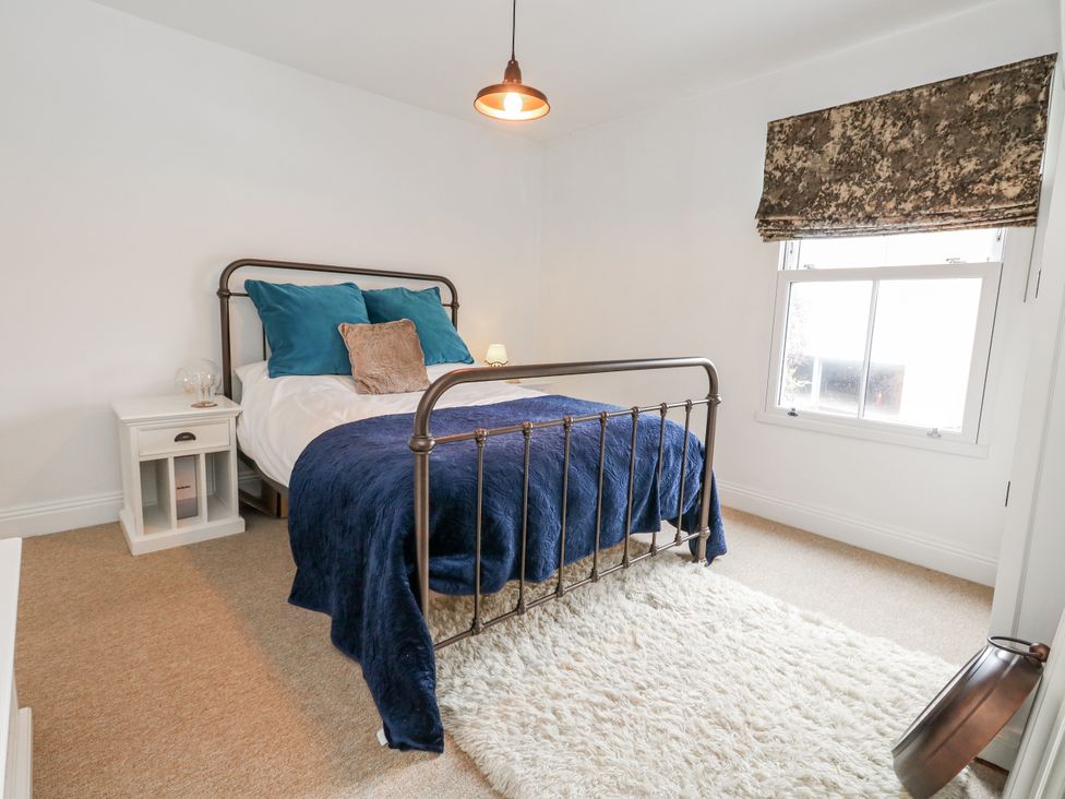 A bedroom with a bed and side table at Fisherman’s Cottage