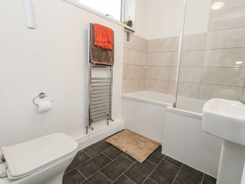 A bathroom featuring a toilet, towel rack, bath, and sink at Fisherman’s Cottage