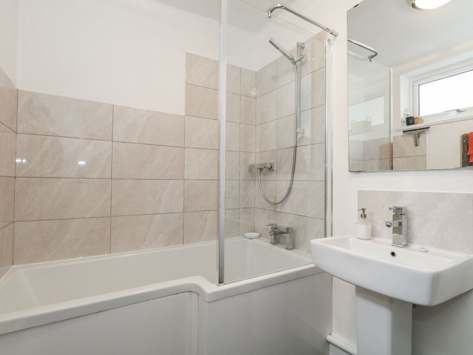 A bathroom featuring a bathtub with shower and a sink at Fisherman’s Cottage