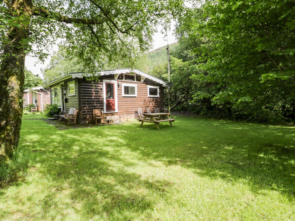 A cabin with a picnic table and chairs surrounded by grass at Ty Bedwen in Dinas Mawddwy