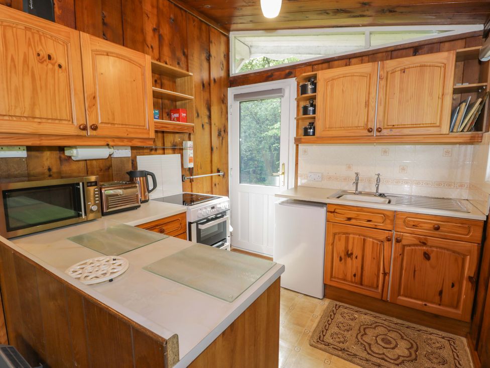 A kitchen with wooden cabinets and appliances at Ty Bedwen in Dinas Mawddwy