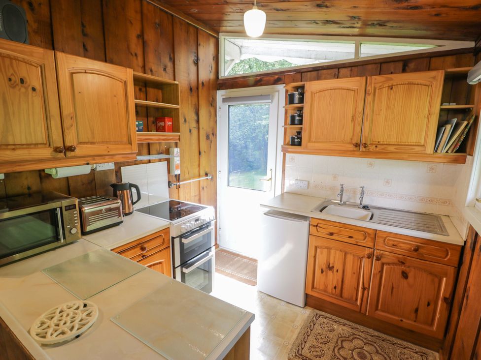 A kitchen with wooden cabinets and appliances at Ty Bedwen in Dinas Mawddwy