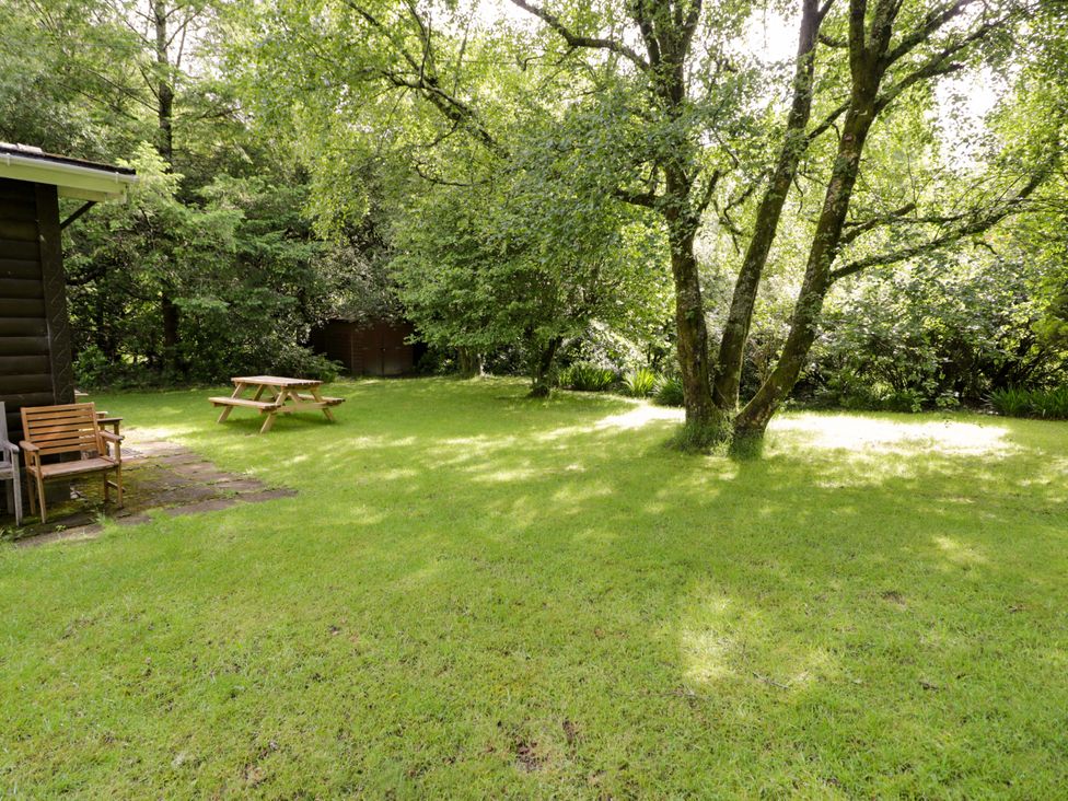 A garden with a table and bench surrounded by trees at Ty Bedwen in Dinas Mawddwy