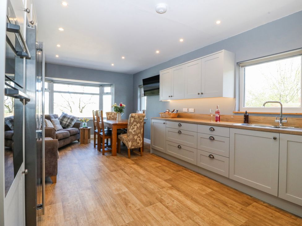 A kitchen with a table and chairs next to a sofa at Tirionfa in Talsarnau