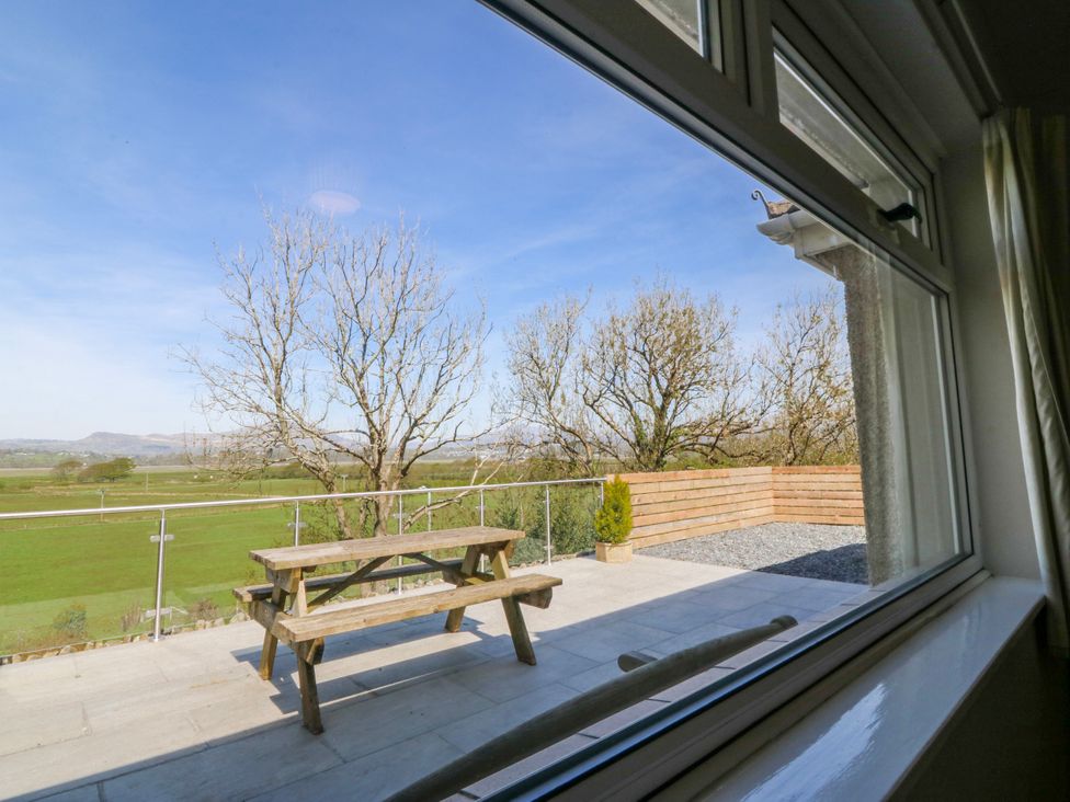 A view of a patio with a table and chairs surrounded by trees at Tirionfa in Talsarnau