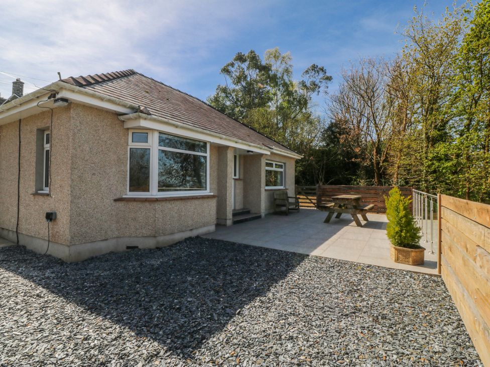 An outdoor area with a house, garden table, and gravel at Tirionfa, Talsarnau