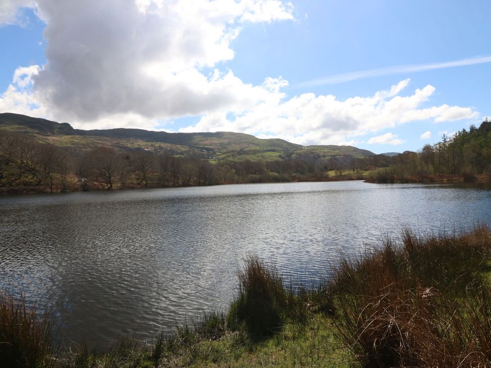A lake surrounded by mountains and trees at Tirionfa in Talsarnau