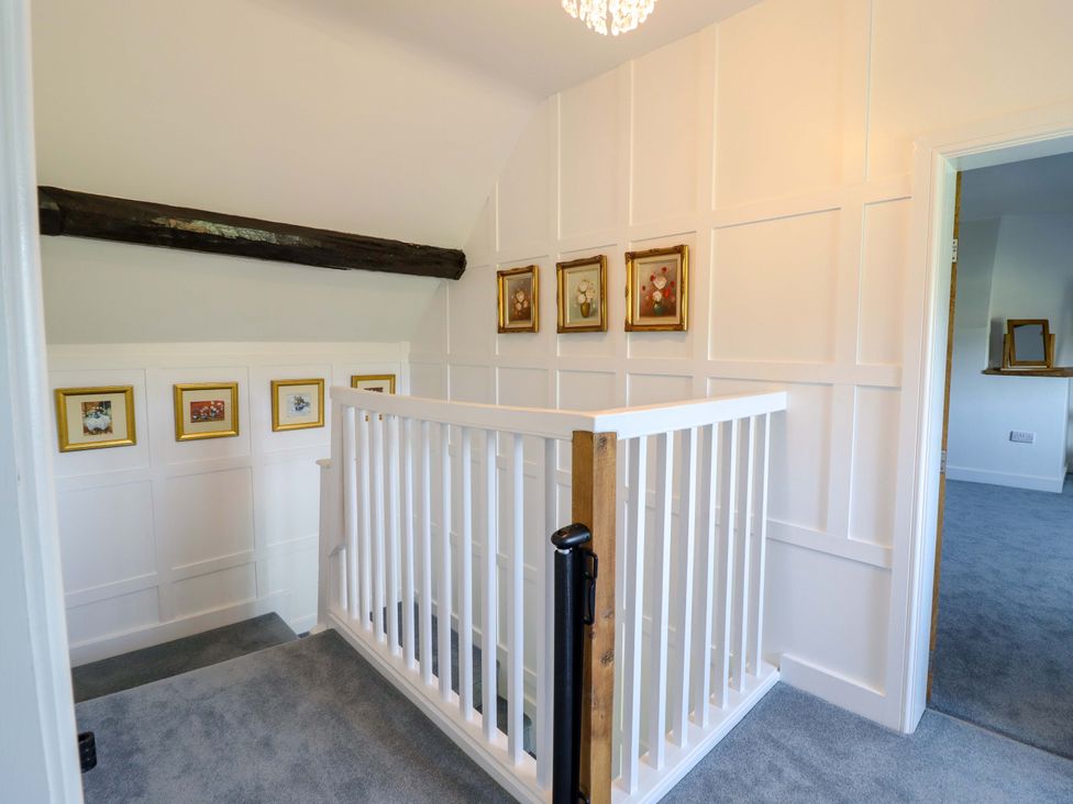 A hallway with a stair railing and pictures at Upper Dolarddyn in Castle Caereinion
