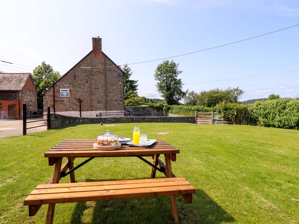 A garden with a wooden table and drinks at Upper Dolarddyn in Castle Caereinion