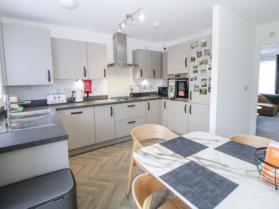 A kitchen with cabinets, stove, sink, and a dining table at Peak Avenue Retreat in Wingerworth near Chesterfield