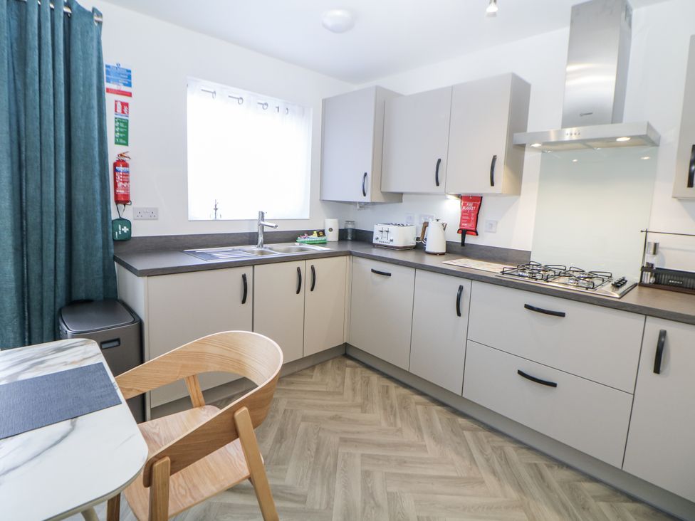 A kitchen with cabinets, sink, stove, and table at Peak Avenue Retreat in Wingerworth near Chesterfield