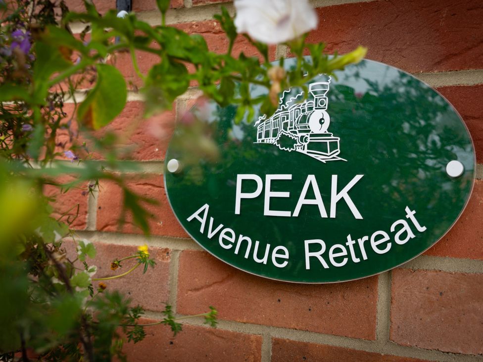 A sign displaying Peak Avenue Retreat on a brick wall in Wingerworth near Chesterfield