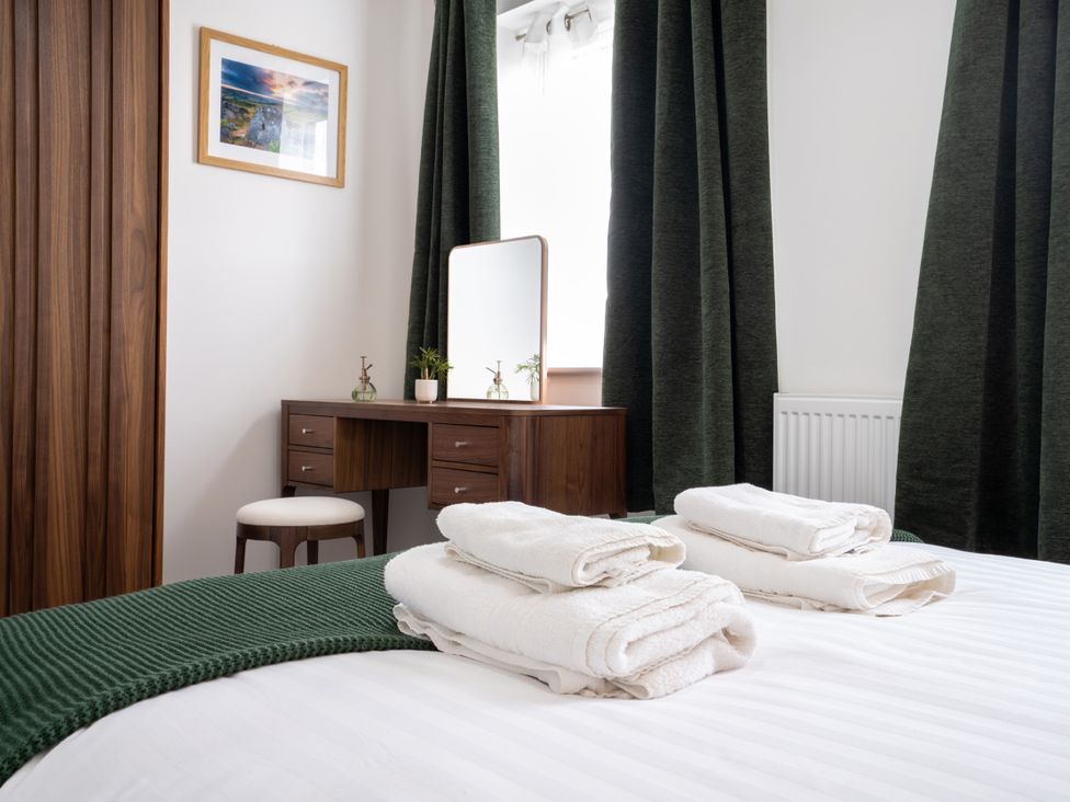 A bedroom with a bed, towels on it, and a vanity with a mirror at Peak Avenue Retreat in Wingerworth near Chesterfield