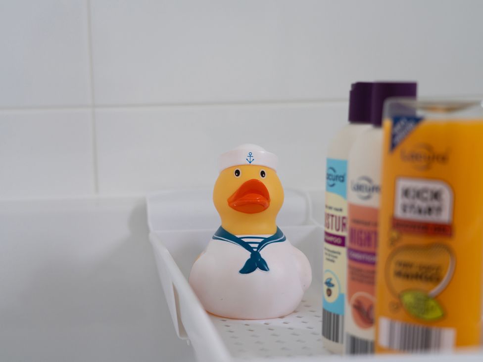 A bath mat with a rubber duck and various bottle toiletries at Peak Avenue Retreat Wingerworth near Chesterfield