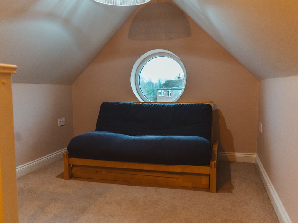 A small room with a sofa bed and a round window at Willow Garth Roecliffe near Boroughbridge