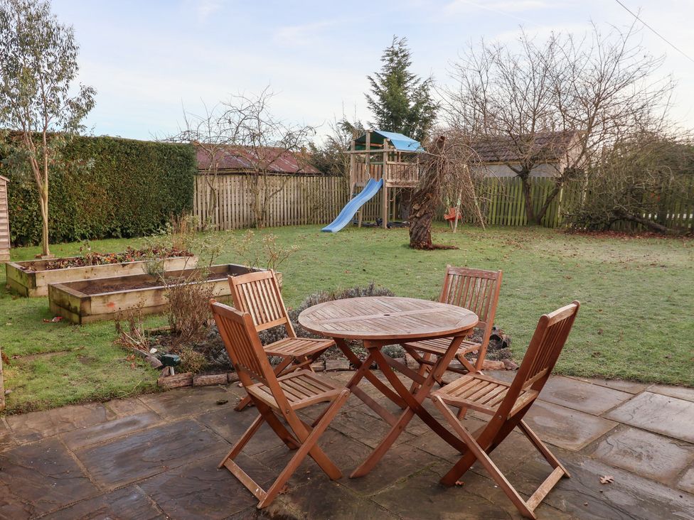 A garden with a table, chairs, and a playground at Willow Garth in Roecliffe near Boroughbridge