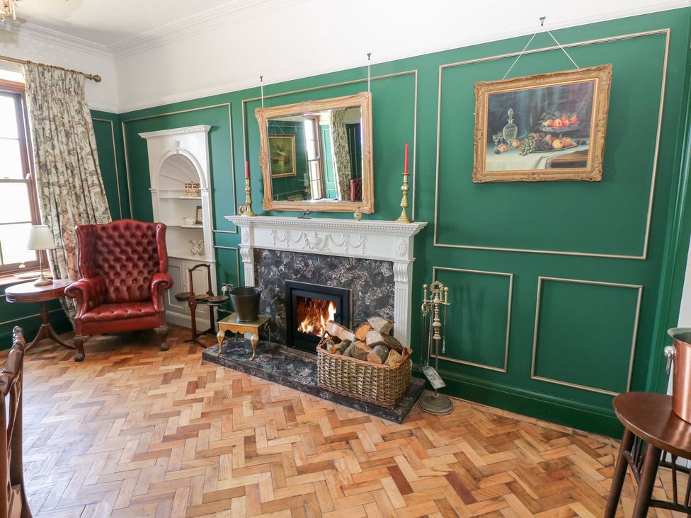 A living room with a fireplace and armchair at Coytrahen House Coytrahen near Bettws