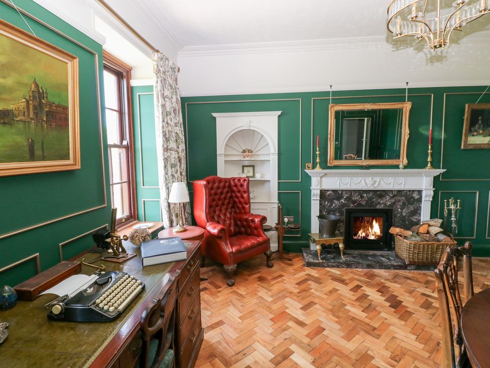 A sitting room with an armchair and typewriter at Coytrahen House in Coytrahen near Bettws