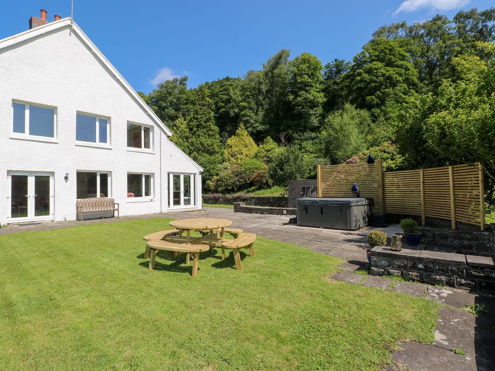 A garden with picnic table and hot tub at Coytrahen House in Coytrahen near Bettws