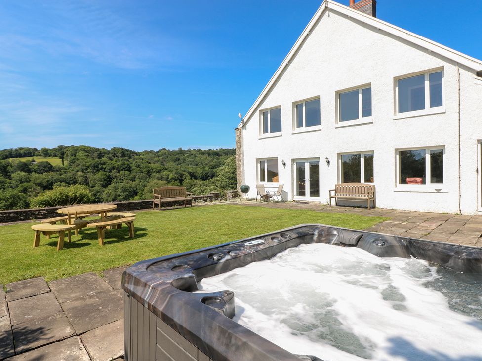 A garden with a hot tub and seating area at Coytrahen House Coytrahen near Bettws
