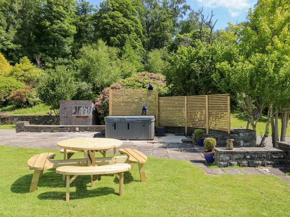 A garden with a hot tub and an outdoor table at Coytrahen House in Coytrahen near Bettws