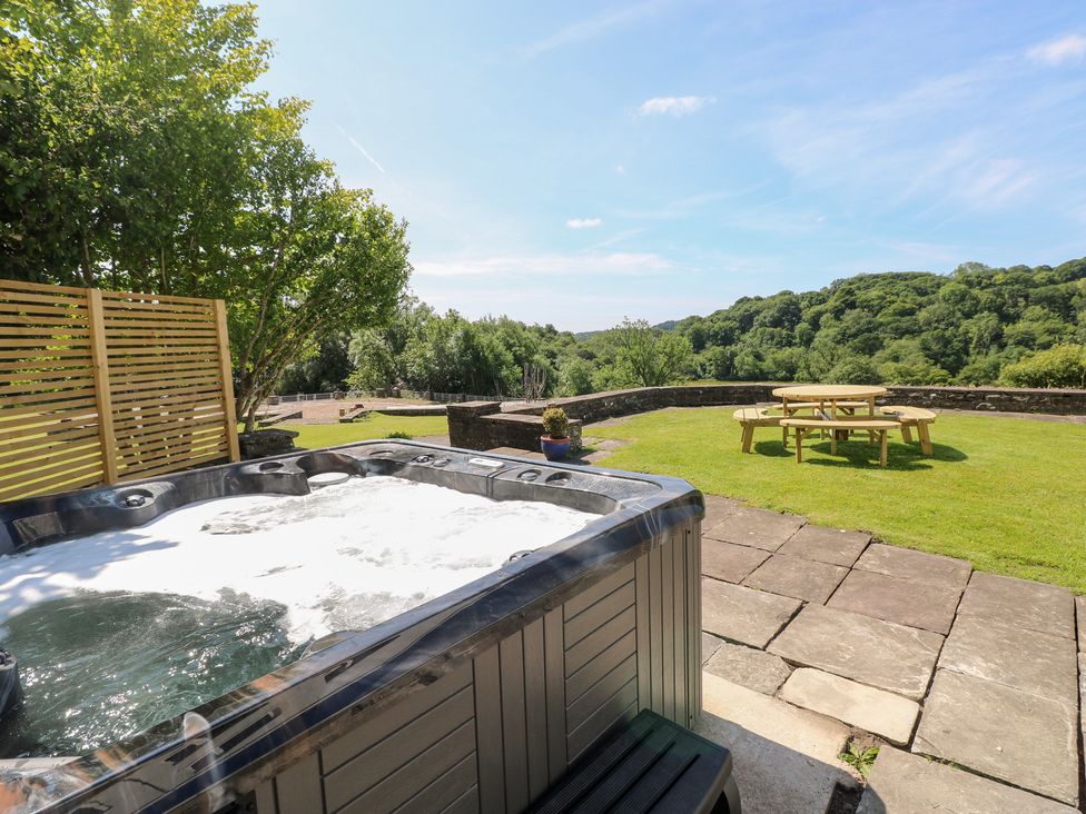 A hot tub with a picnic table in the garden at Coytrahen House near Bettws