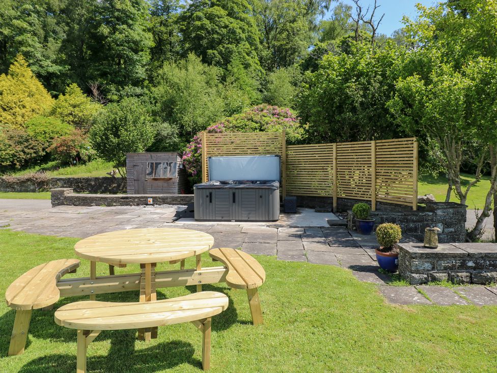 A garden with a hot tub and an outdoor dining table at Coytrahen House near Bettws