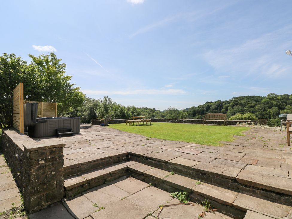An outdoor space with a hot tub and benches at Coytrahen House Coytrahen near Bettws