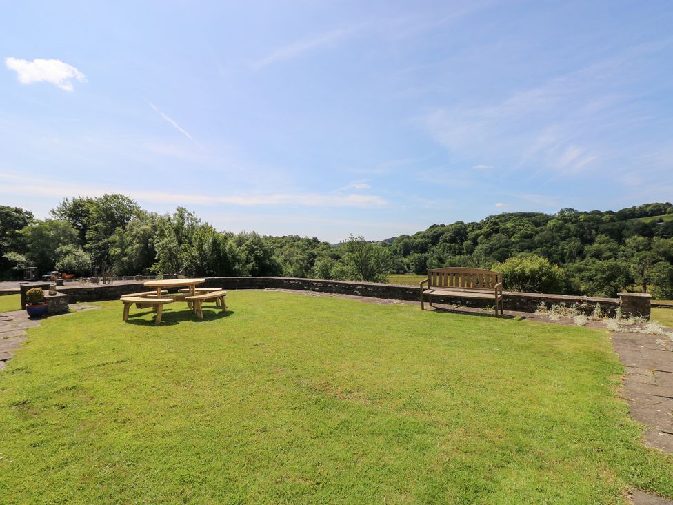 A garden with a table and bench at Coytrahen House near Bettws