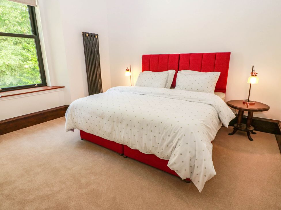 A bedroom with a red bed and a bedside table at Winnocklands House
