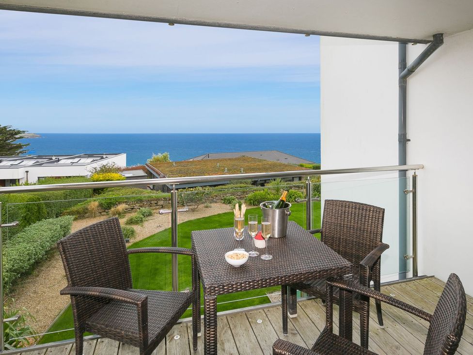 A balcony with a table and chairs overlooking the sea at Far Cliffs in St. Ives