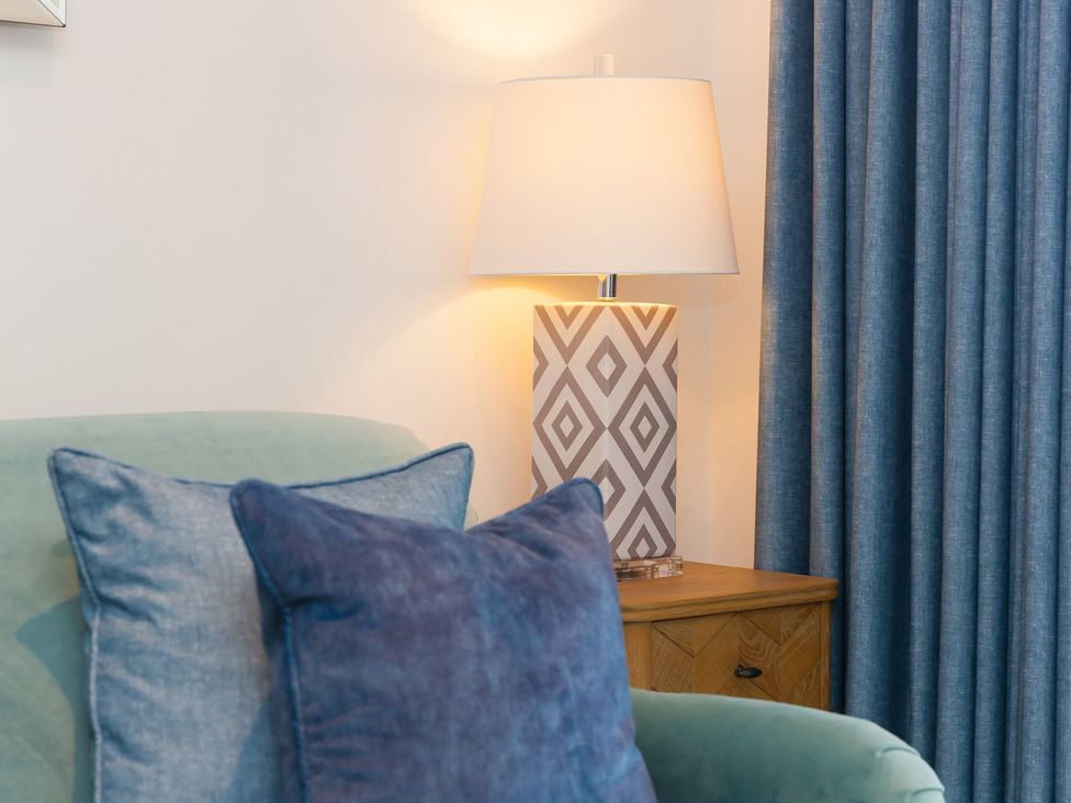 A living room with a lamp and cushions at Far Cliffs in St. Ives