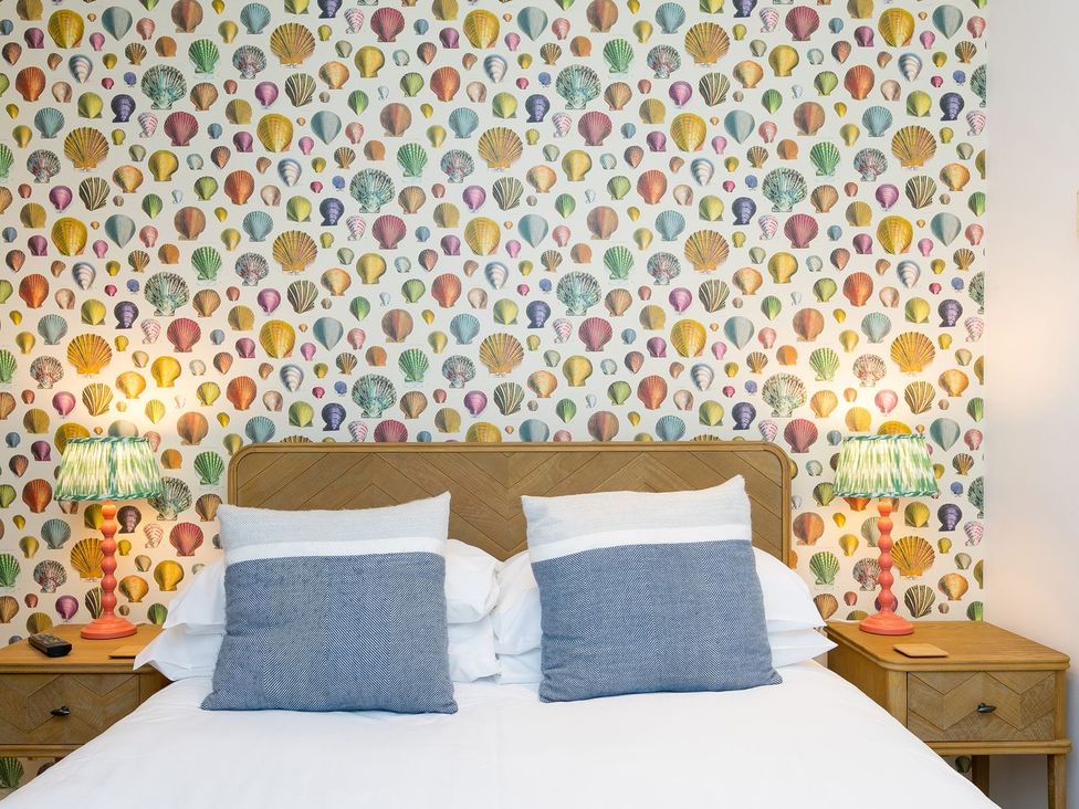 A bedroom with a patterned wallpaper and a bed at Far Cliffs in St. Ives