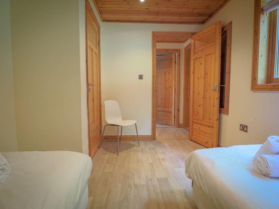 A bedroom with two beds and a chair at Lodge 68 - Fern Gully near Chudleigh