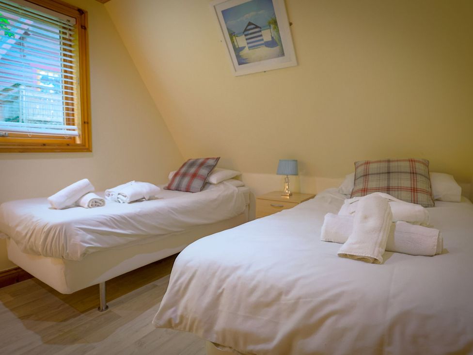 A bedroom with two beds and a nightstand at Lodge 68 - Fern Gully near Finlakes Holiday Park