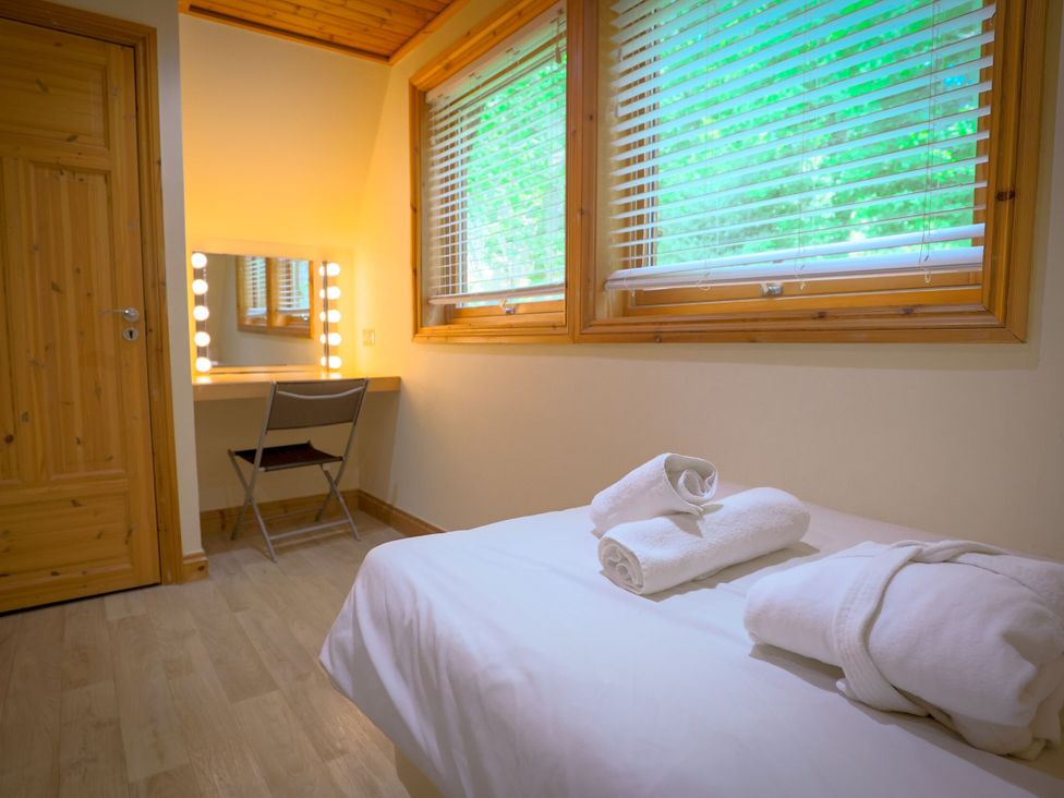 A bedroom with towels on a bed and a vanity mirror at Lodge 68 - Fern Gully near Finlakes Holiday Park
