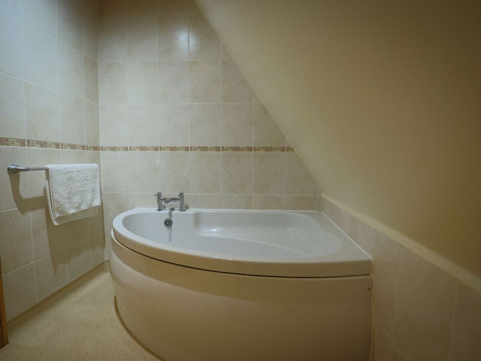 A bathroom with a bathtub and towel rail at Lodge 68 - Fern Gully near Finlakes Holiday Park