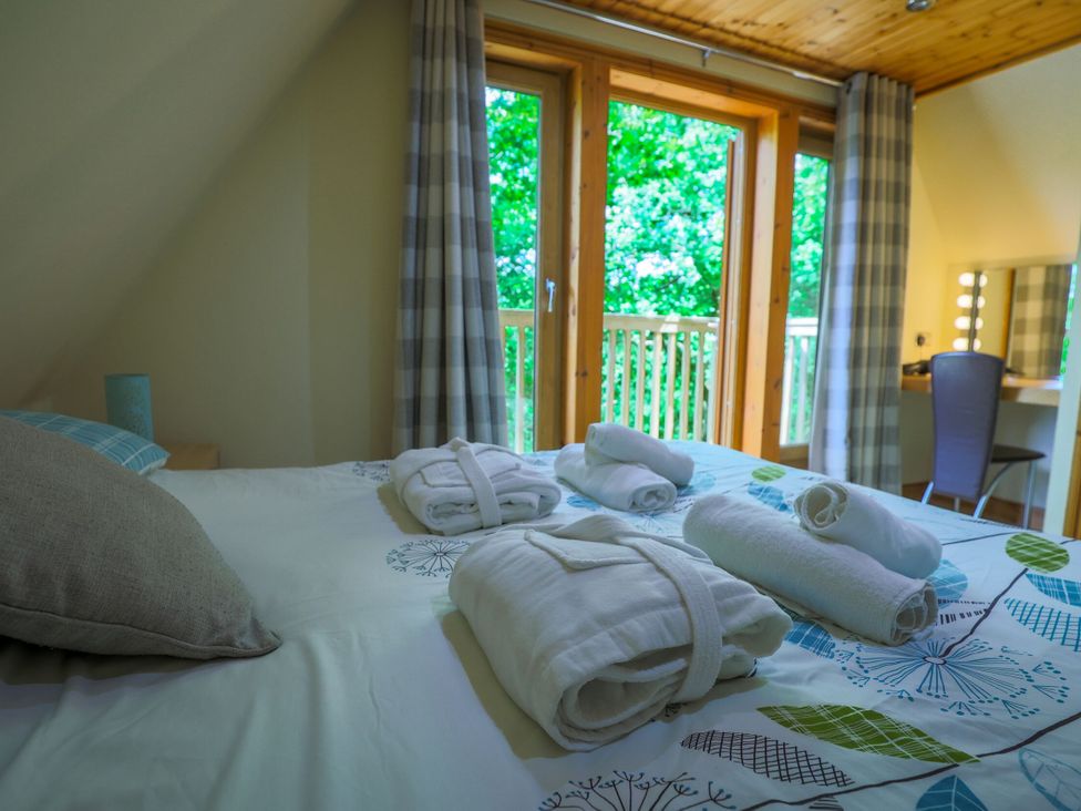A bedroom with a bed covered in linens and towels at Lodge 68 - Fern Gully near Finlakes Holiday Park
