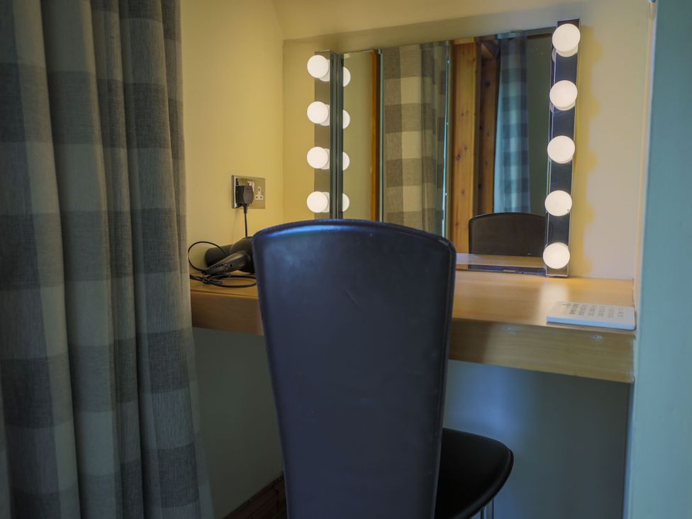 A dressing area with a mirror and chair at Lodge 68 - Fern Gully near Chudleigh