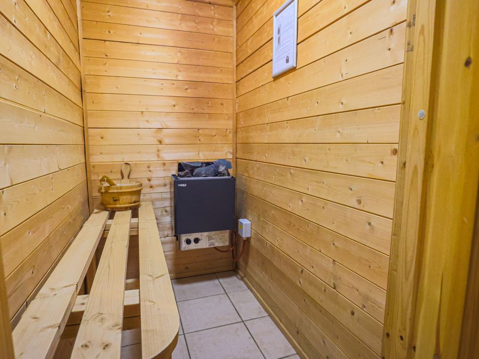 A sauna with a wooden bench and stove at Lodge 68 - Fern Gully Finlakes Holiday Park near Chudleigh