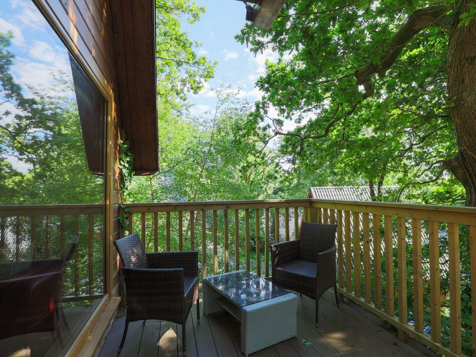 A balcony with chairs and a table surrounded by trees at Lodge 68 - Fern Gully near Chudleigh