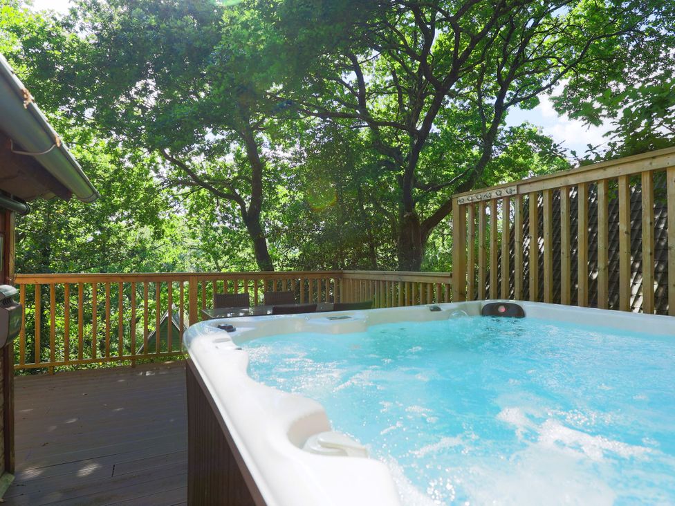 A hot tub on a wooden deck surrounded by trees at Lodge 68 - Fern Gully near Finlakes Holiday Park