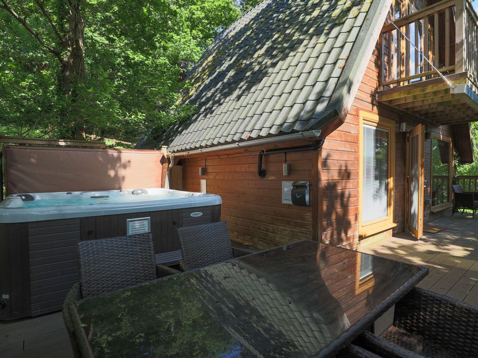An outdoor area with a hot tub and wooden cabin at Lodge 68 - Fern Gully near Finlakes Holiday Park