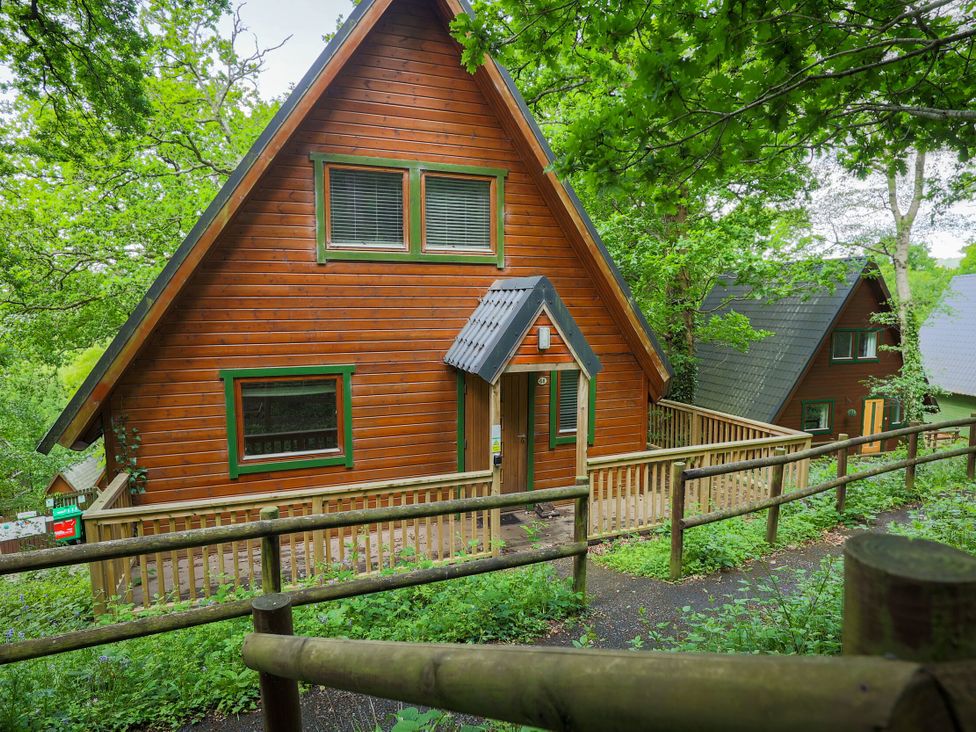 A wooden lodge with a deck and pathway at Lodge 68 - Fern Gully near Finlakes Holiday Park near Chudleigh